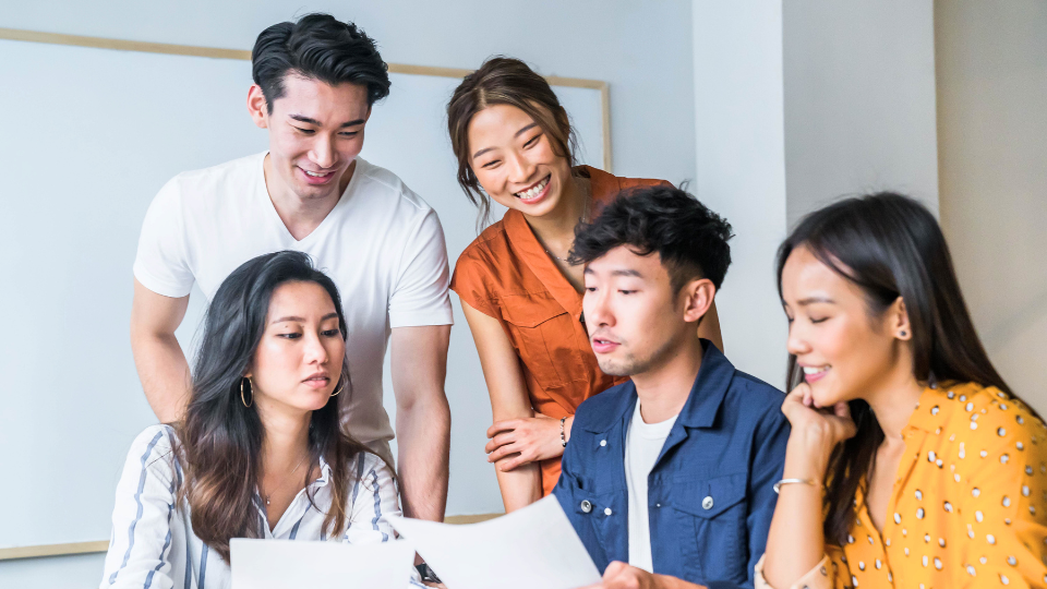 Five people collaborating around the table with documents