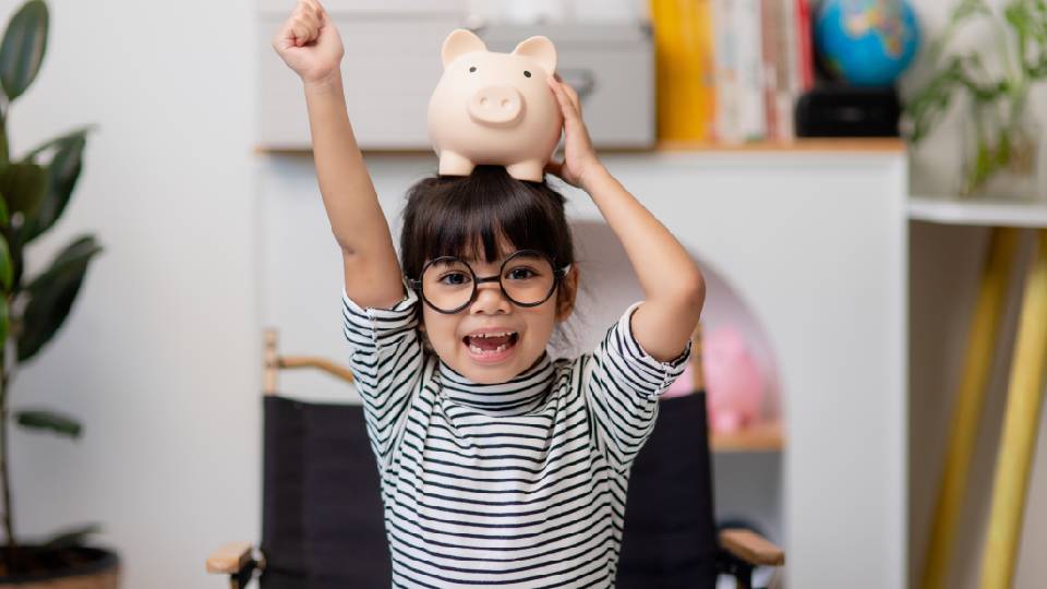Little girl saving money in a piggy bank, learning about saving, Kid save money for future education.