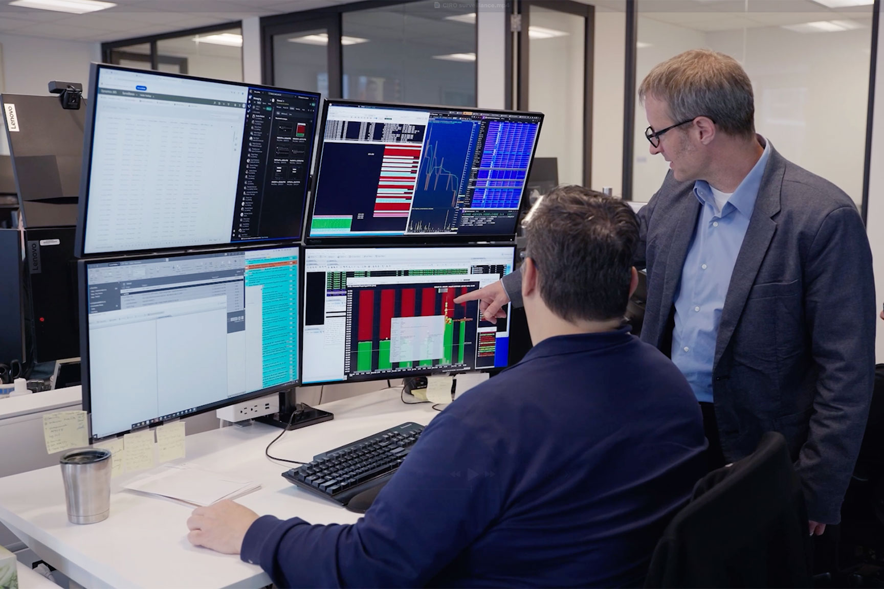 Two men collaborating facing computer monitor screens