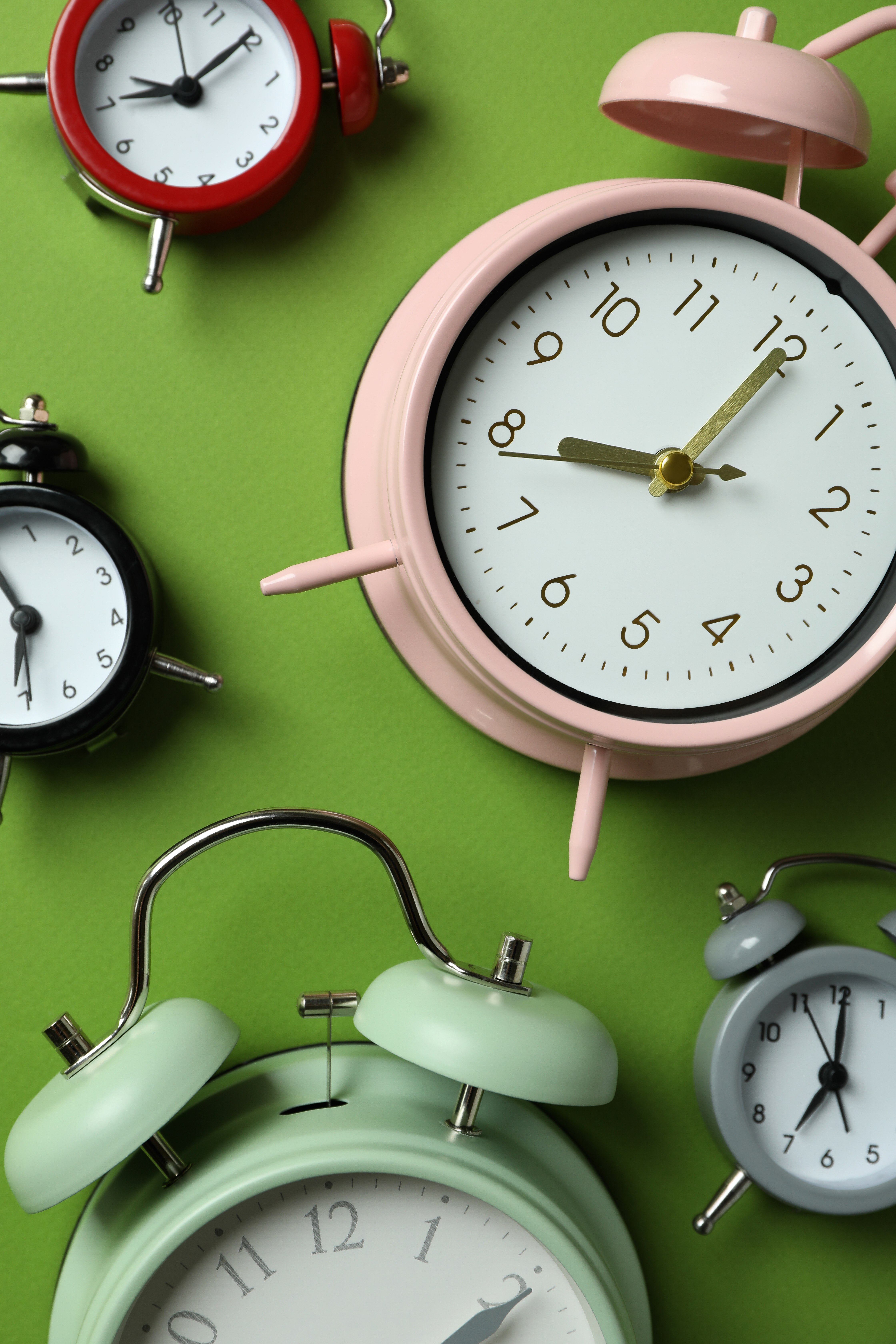 collection of colorful alarm clocks on green background